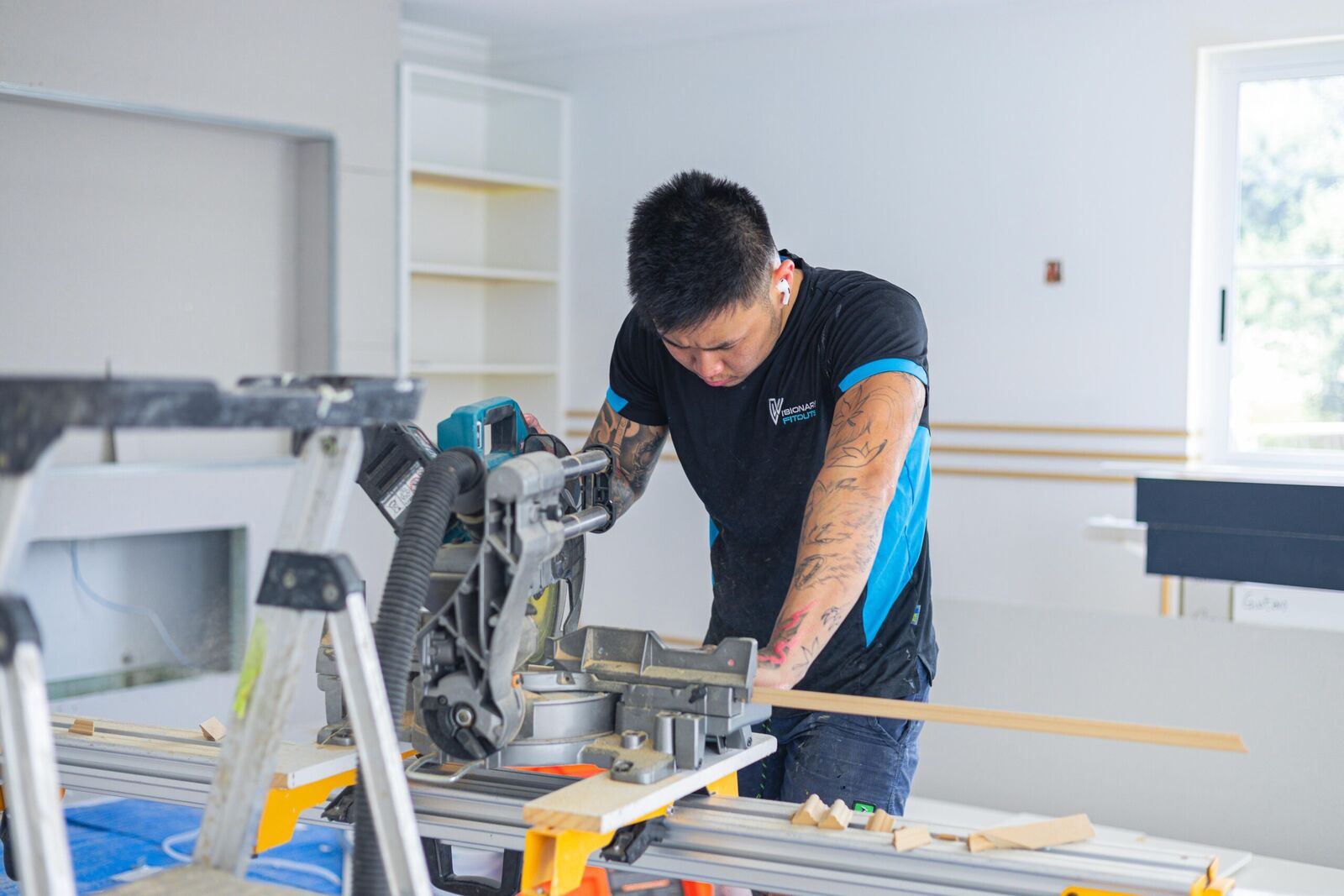 Carpenter cutting architrave on a mitre saw in a renovated home