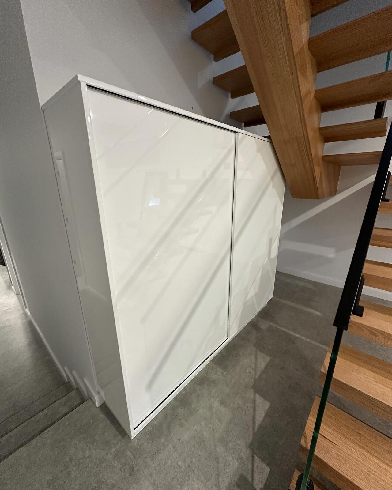 Custom under-stair storage joinery with timber staircase above