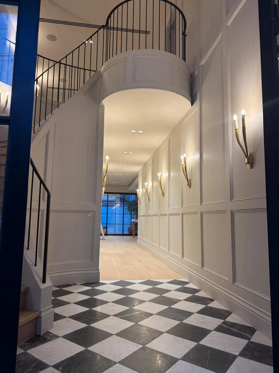 Panelled entrance with a curved staircase and chequerboard floor