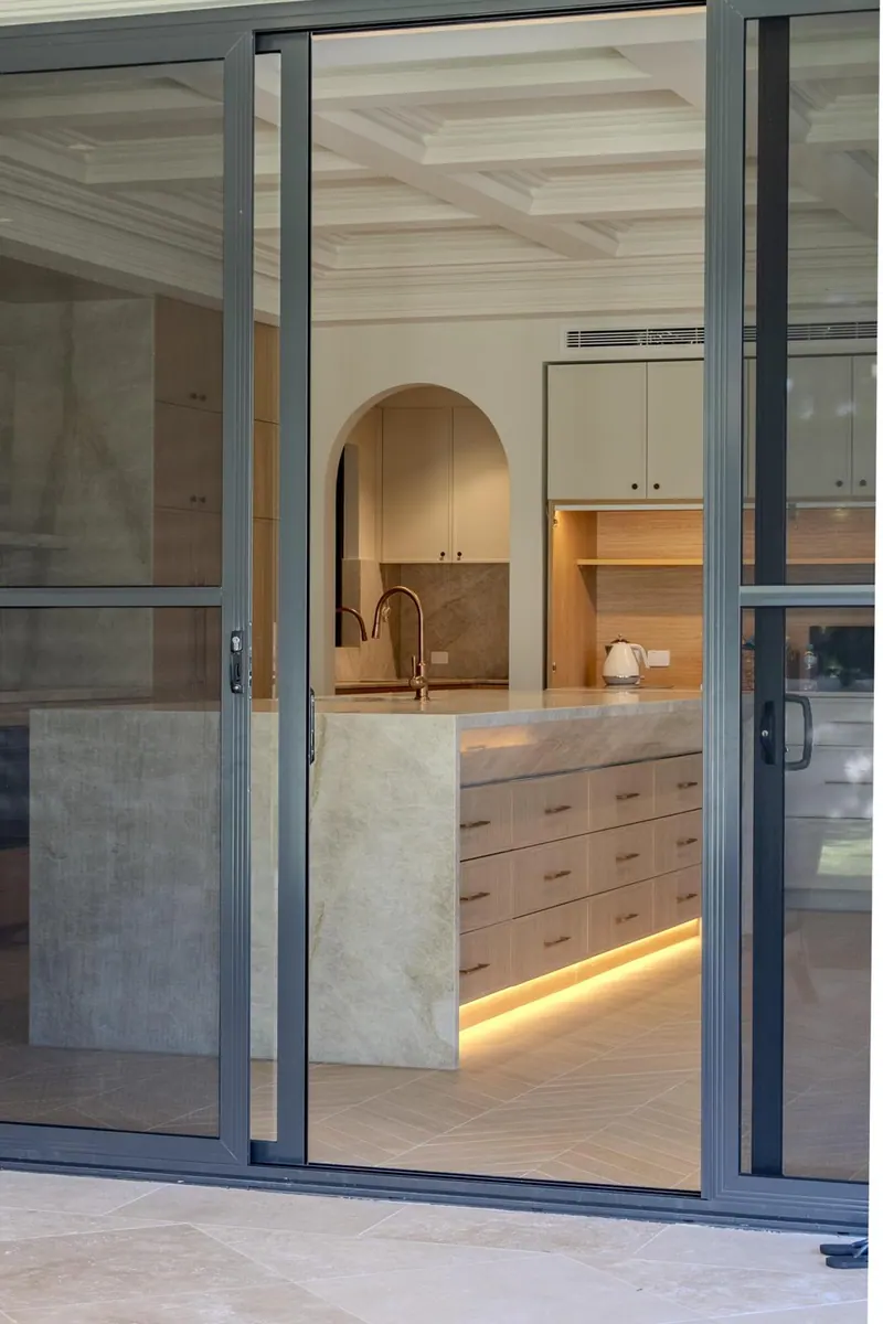 Kitchen joinery seen through black-framed doors