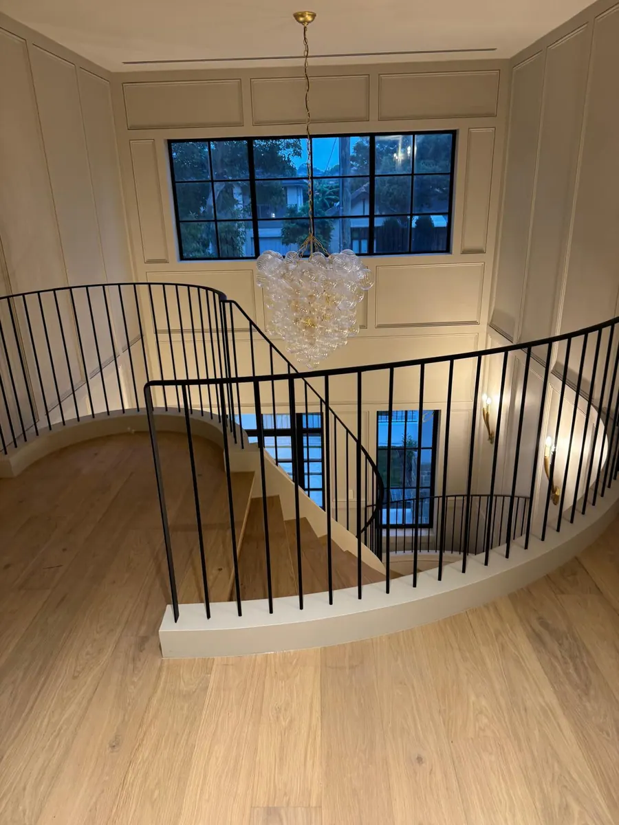 Timber-floored upper landing with a curved balustrade and chandelier