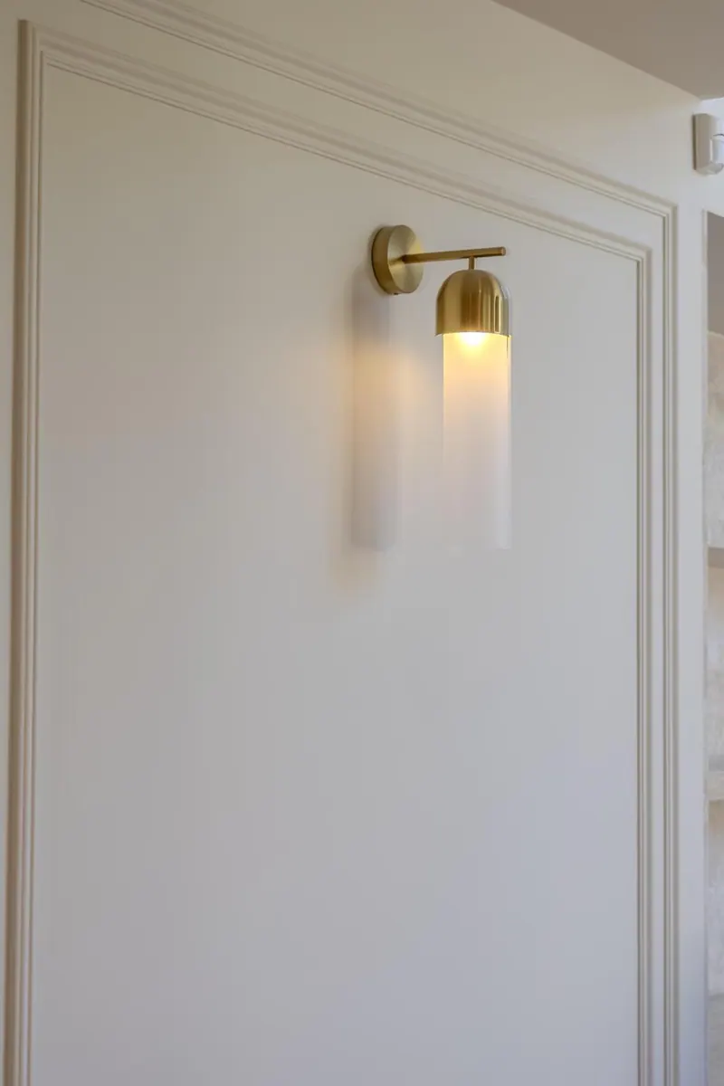 Moulded wall panels and brass wall light beside an interior doorway